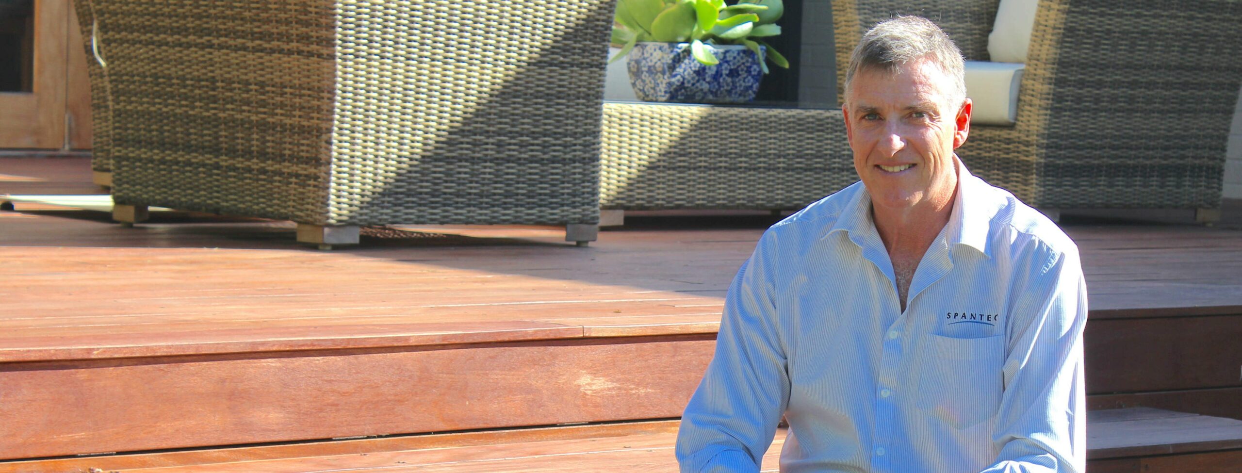 Spantec Director, Roy Beaumont smiling, witting on a deck constructed using Spantec deckframe.