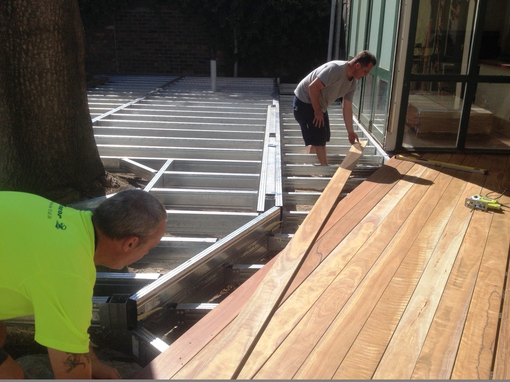 Installation of wide decking boards on a commercial deck at a pub outdoor dining area